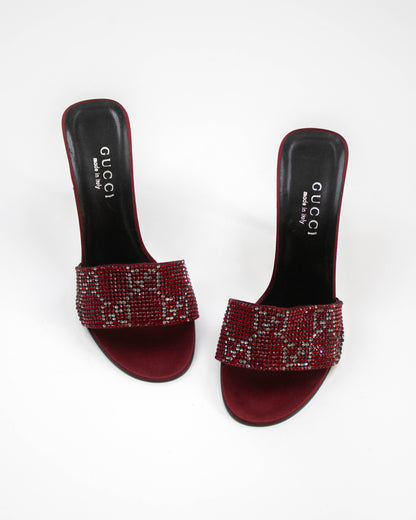 Red high-heeled sandals with rhinestone embellishments on a white background