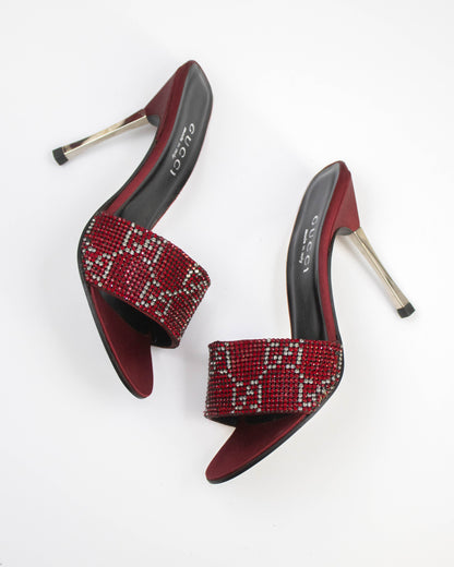 Red high-heeled shoes with rhinestone embellishments on a white background