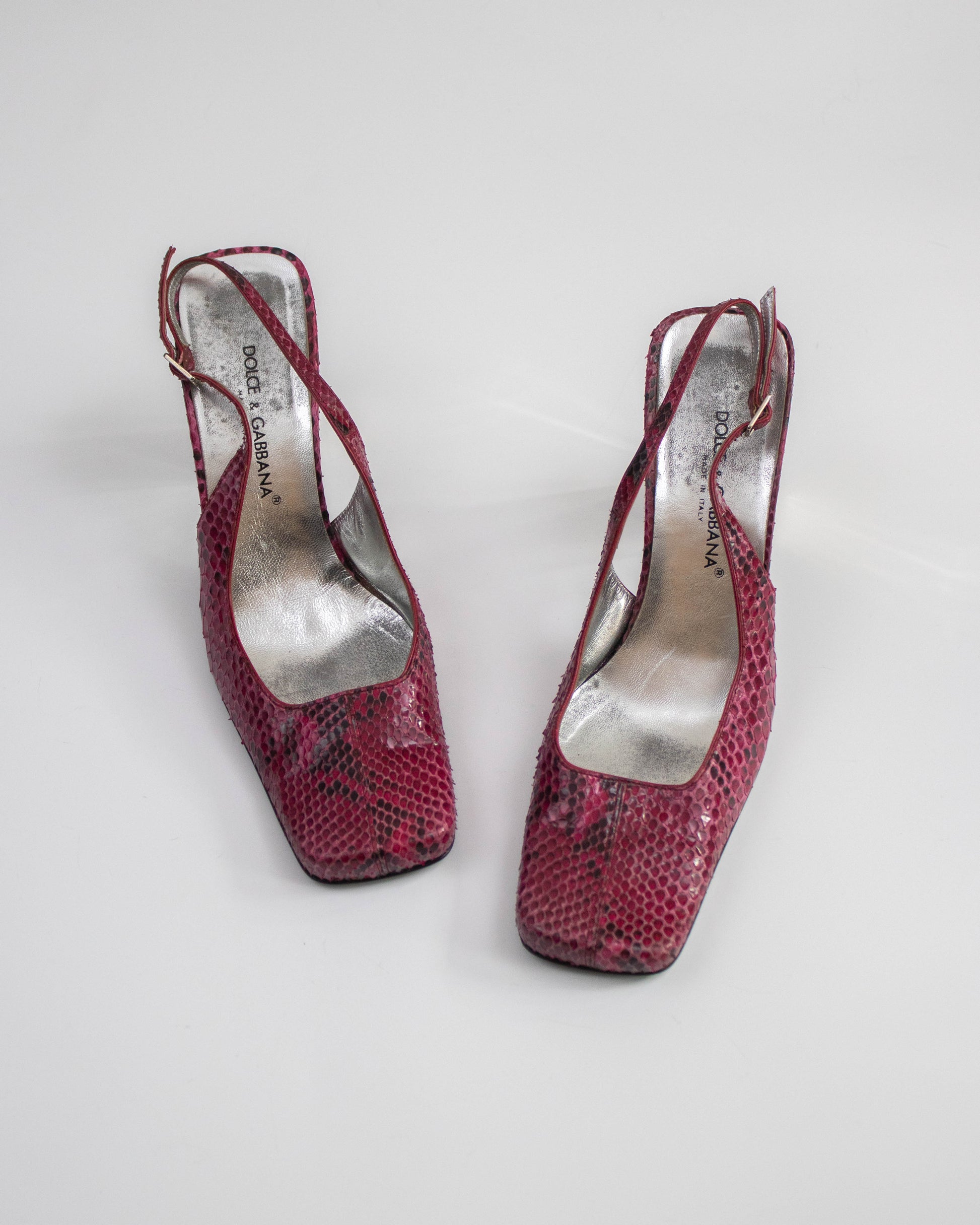Pair of pink high-heeled shoes with 'Dolce&Gabbana' brand name on a white background