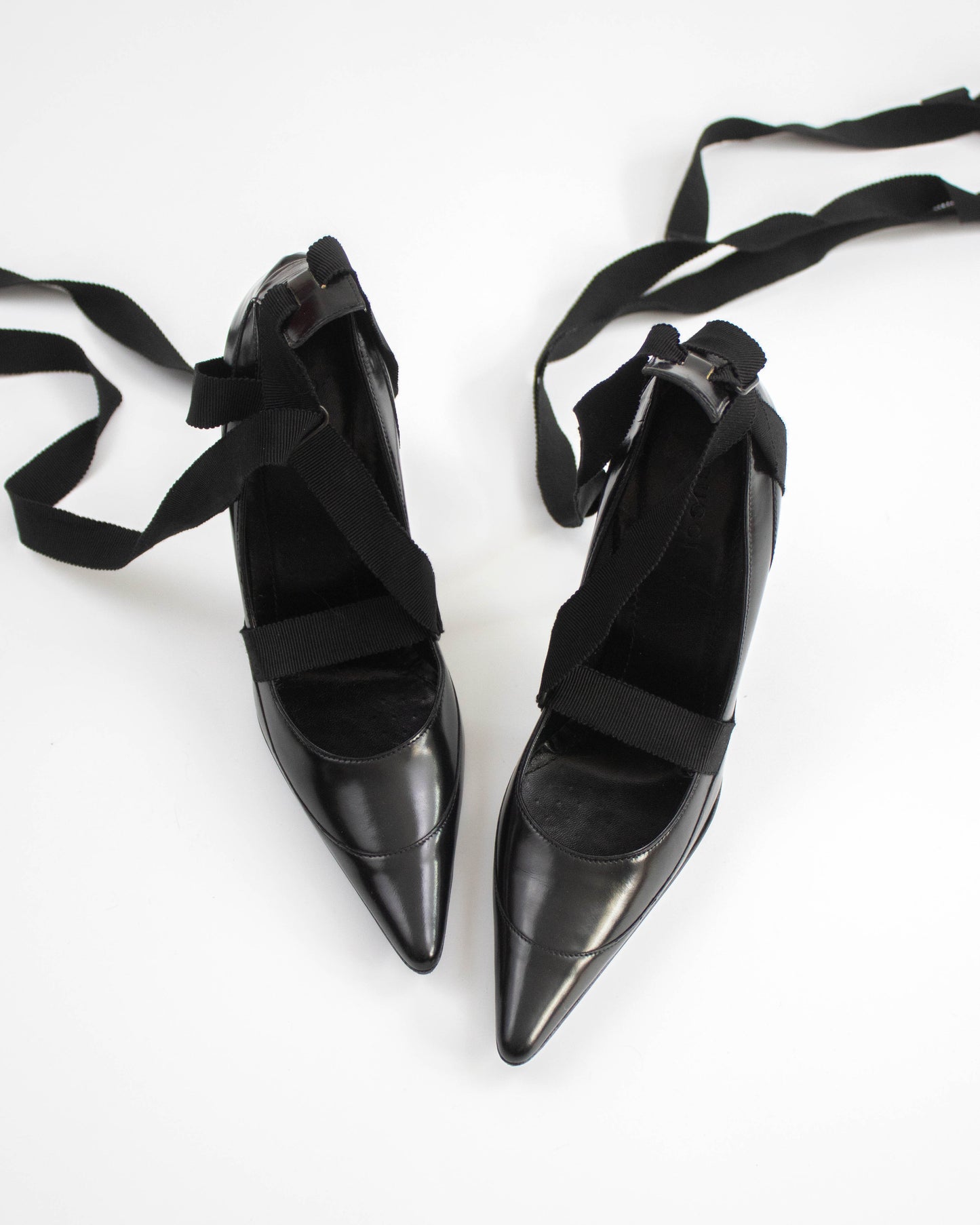 Pair of black pointed-toe Gucci heels with straps top view