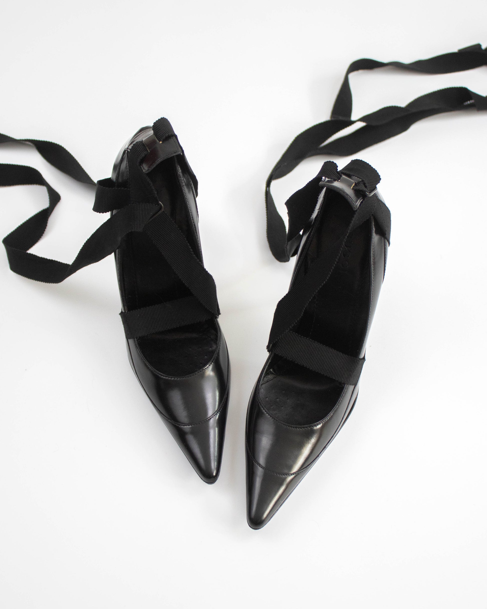 Pair of black pointed-toe Gucci heels with straps top view