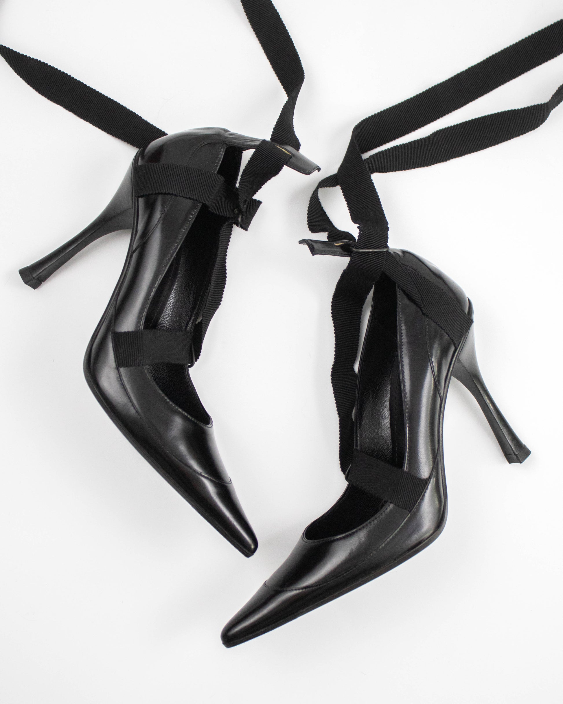 Pair of black pointed-toe Gucci heels with straps side view