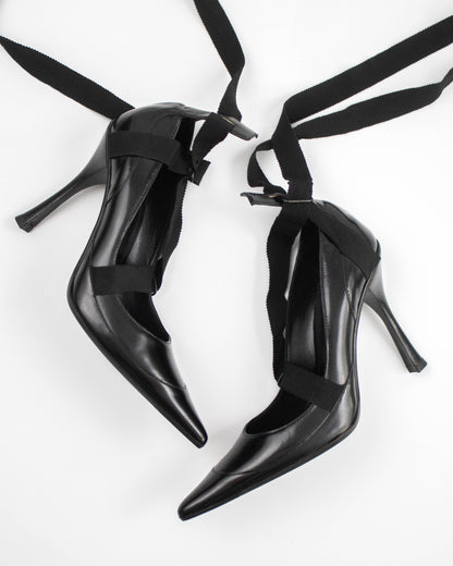 Pair of black pointed-toe Gucci heels with straps side view
