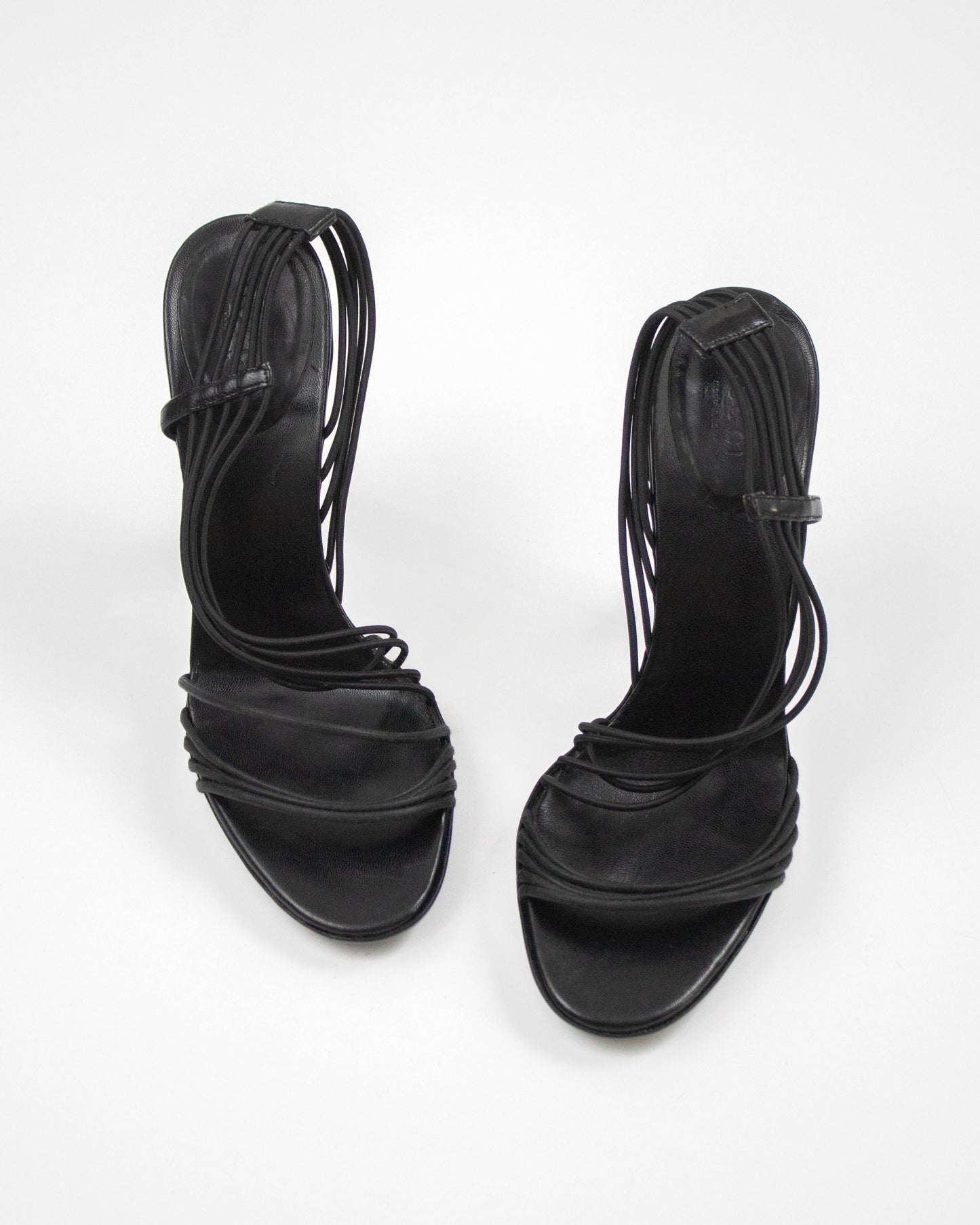 Pair of black strappy high-heeled sandals on a white background