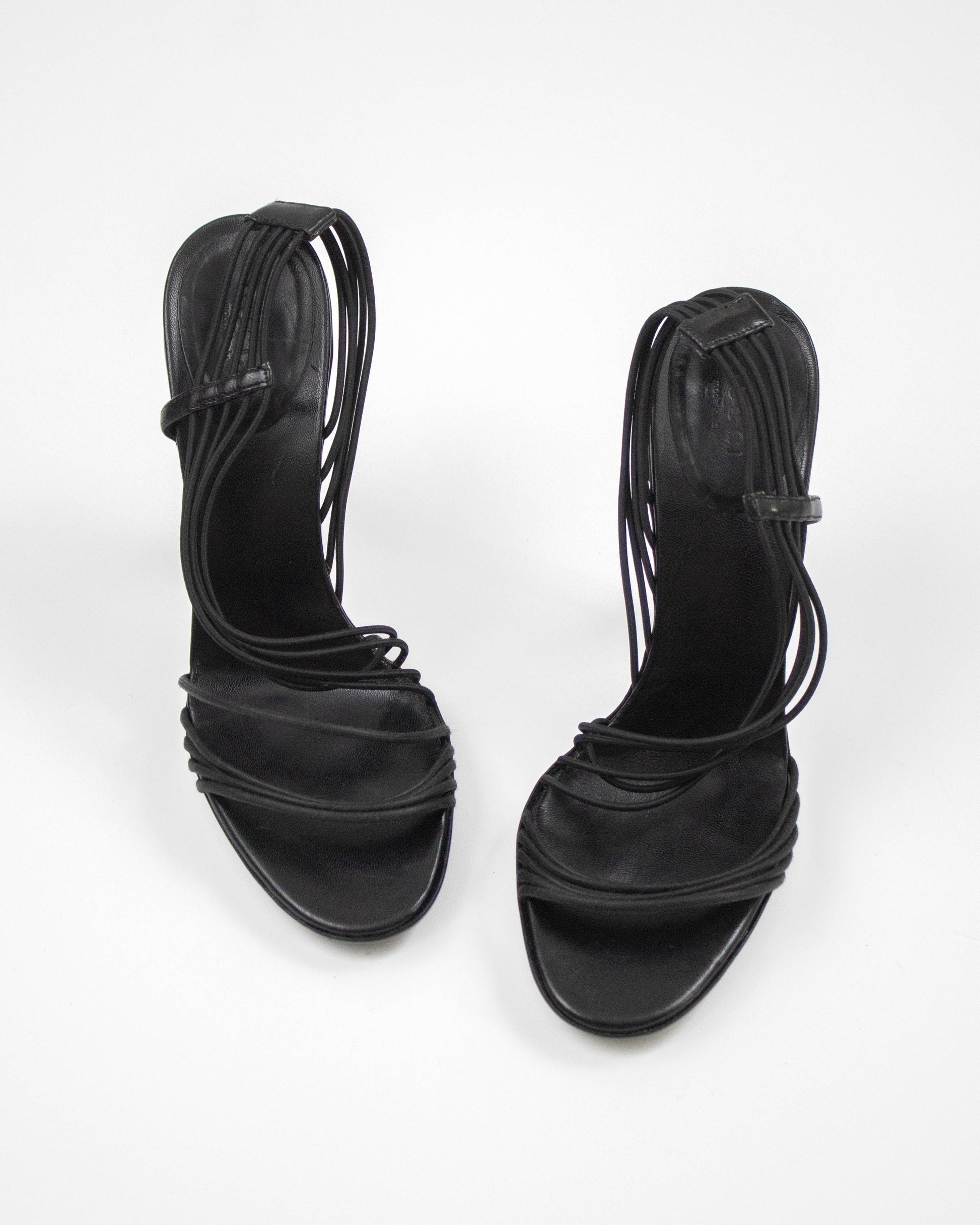 Pair of black strappy high-heeled sandals on a white background