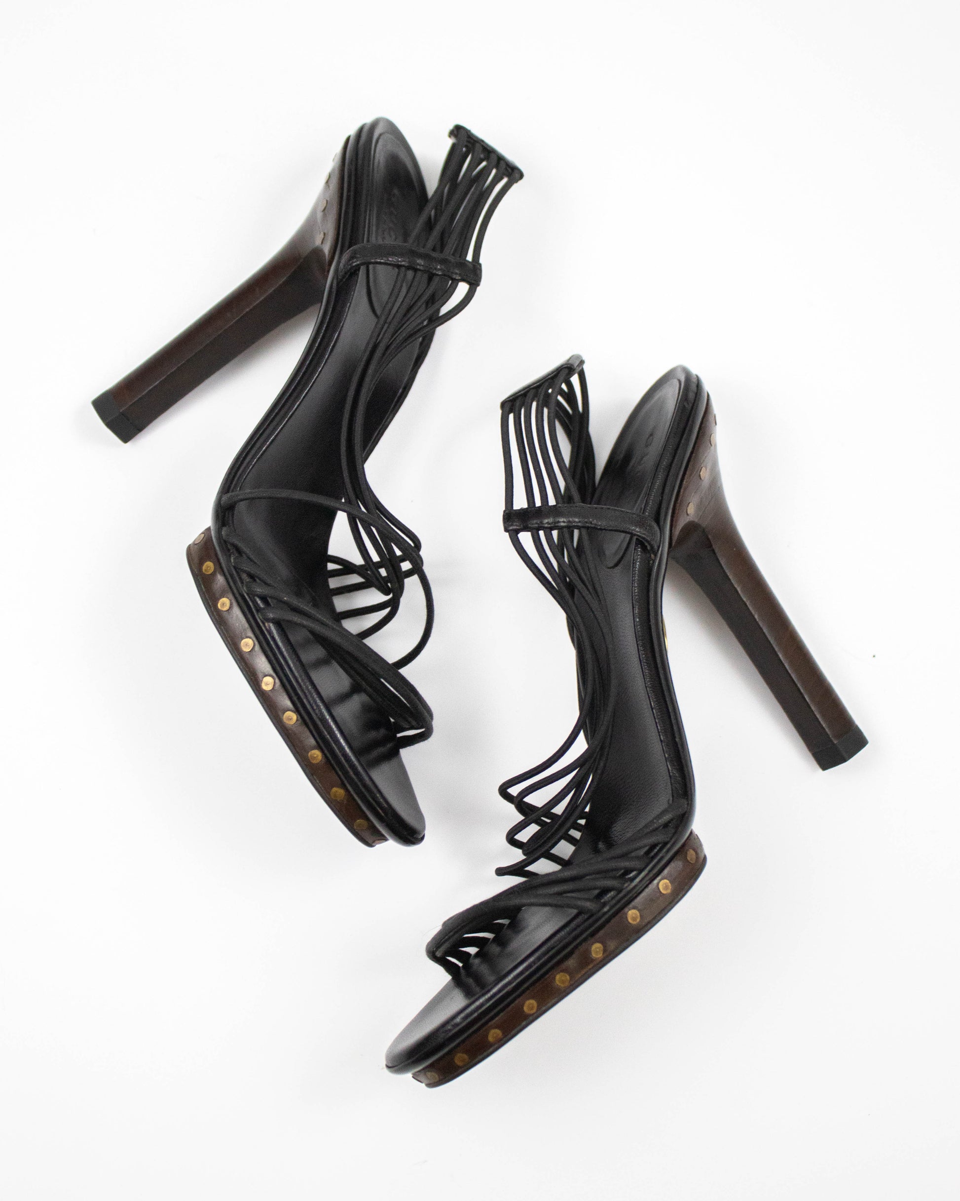 Black high-heeled sandals with studded details on a white background
