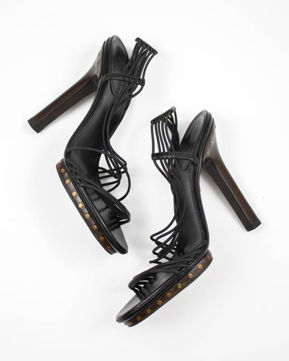 Black high-heeled sandals with studded details on a white background