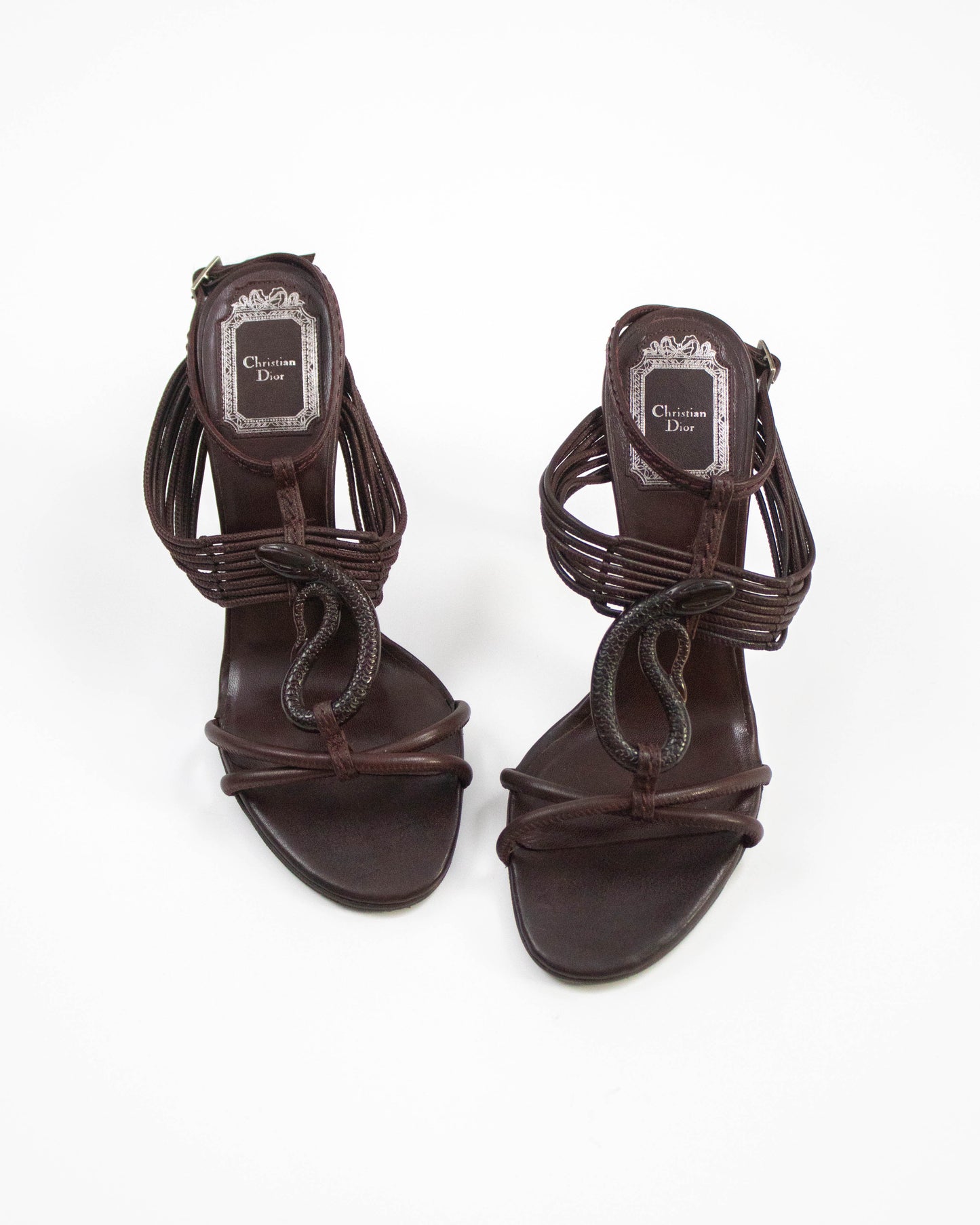 Pair of brown high-heeled sandals with 'Christian Dior' logo on a white background