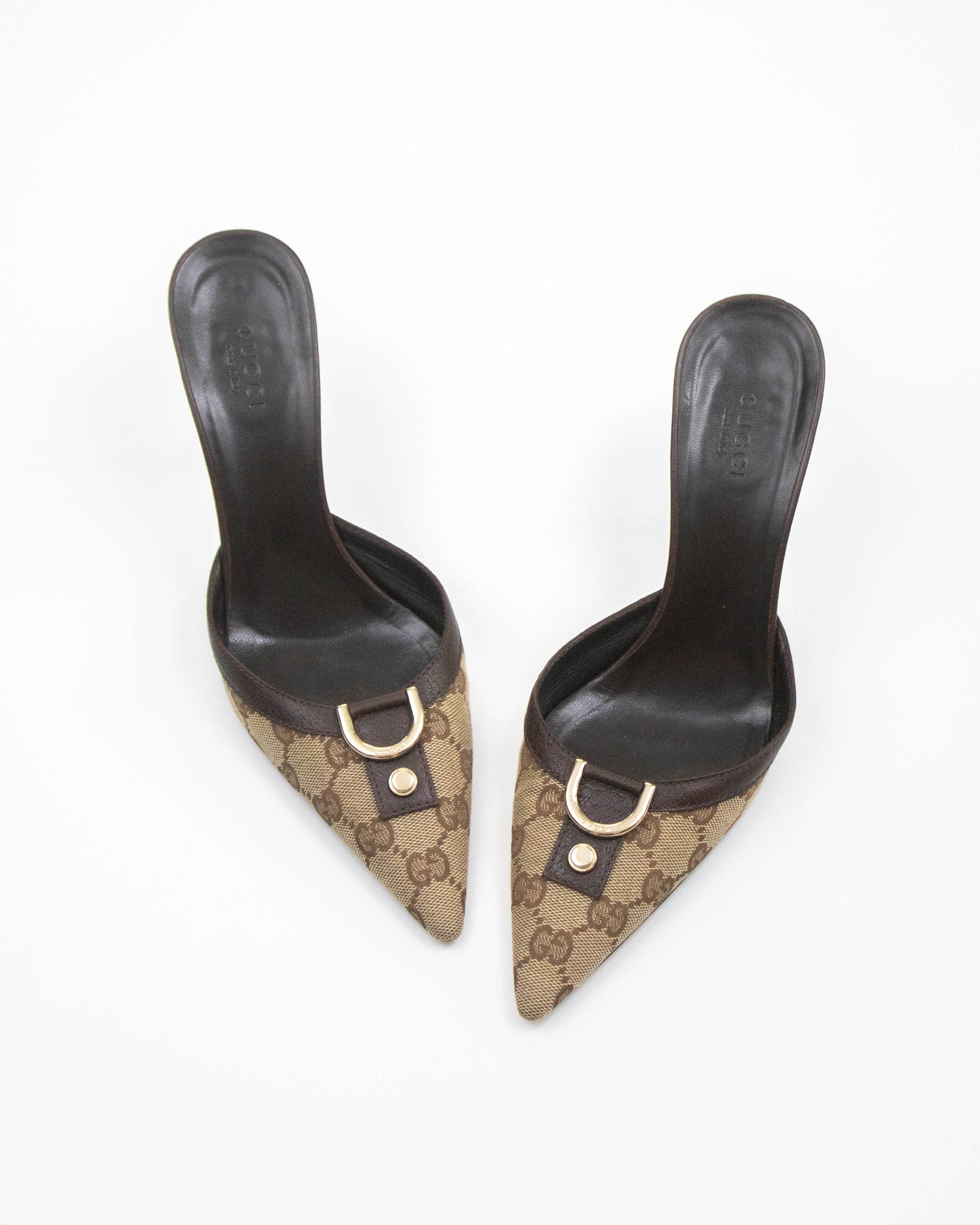 Pair of black high-heeled shoes with Gucci logo on a white background