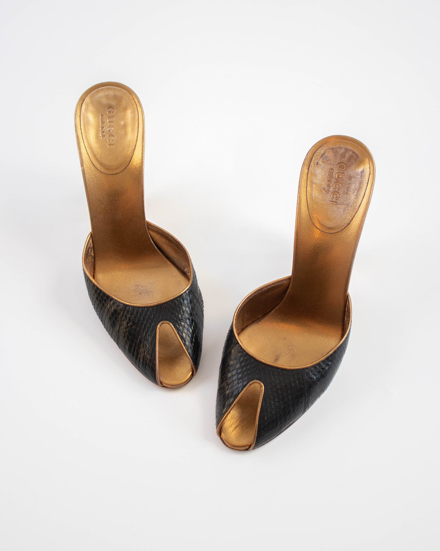 Pair of black high-heeled Gucci shoes with gold soles front view