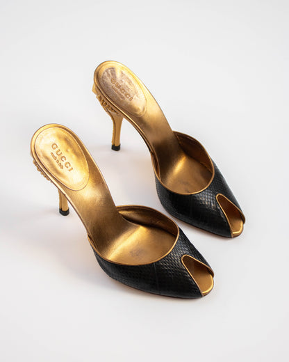 Black and gold high-heeled shoes with 'Gucci' branding side view
