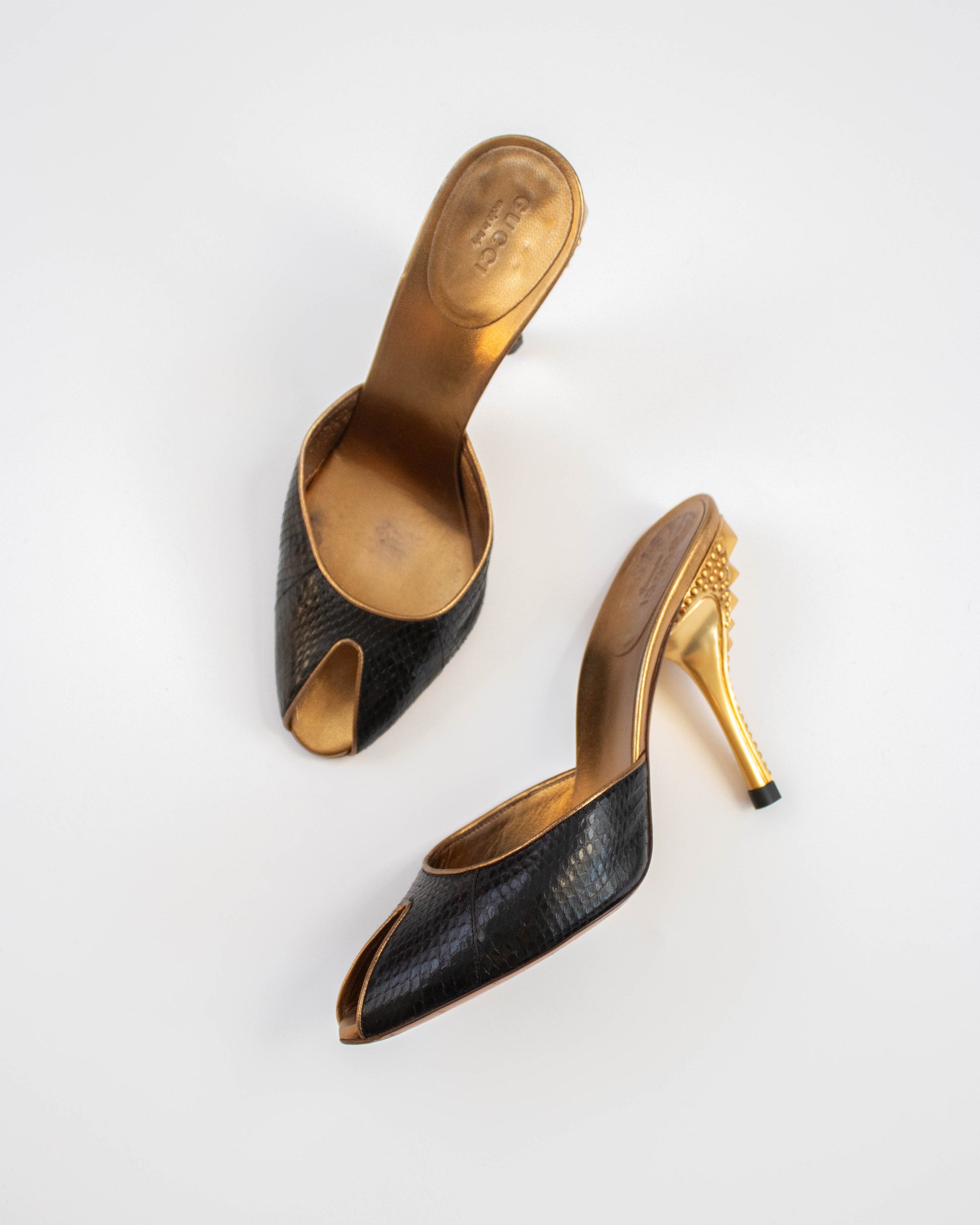 Pair of black high-heeled Gucci shoes with gold soles top view
