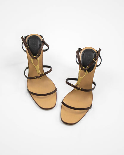 Pair of Gucci high-heeled sandals with brown straps and gold horsebit accents on a white background front view
