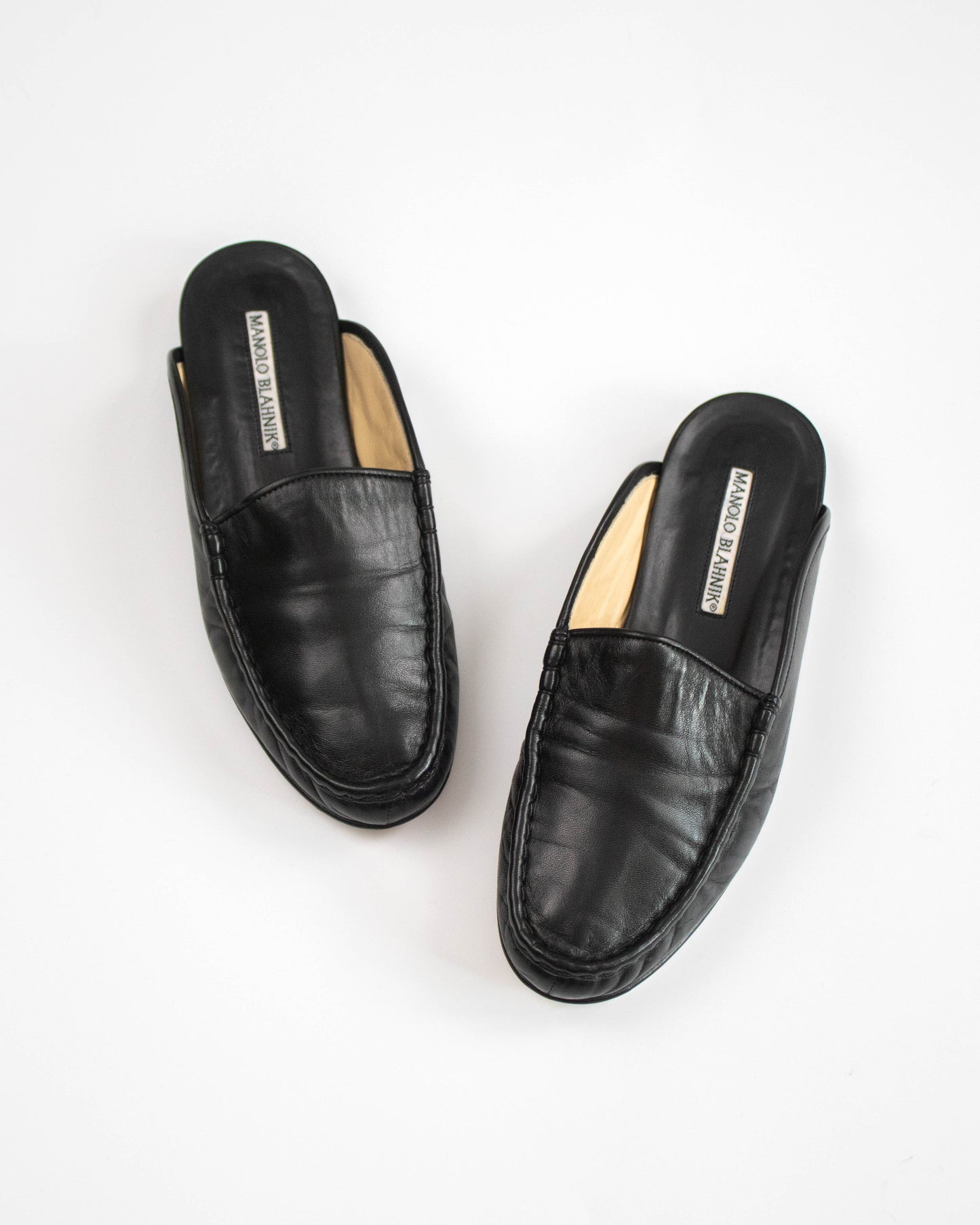 Pair of black leather mules on a white background