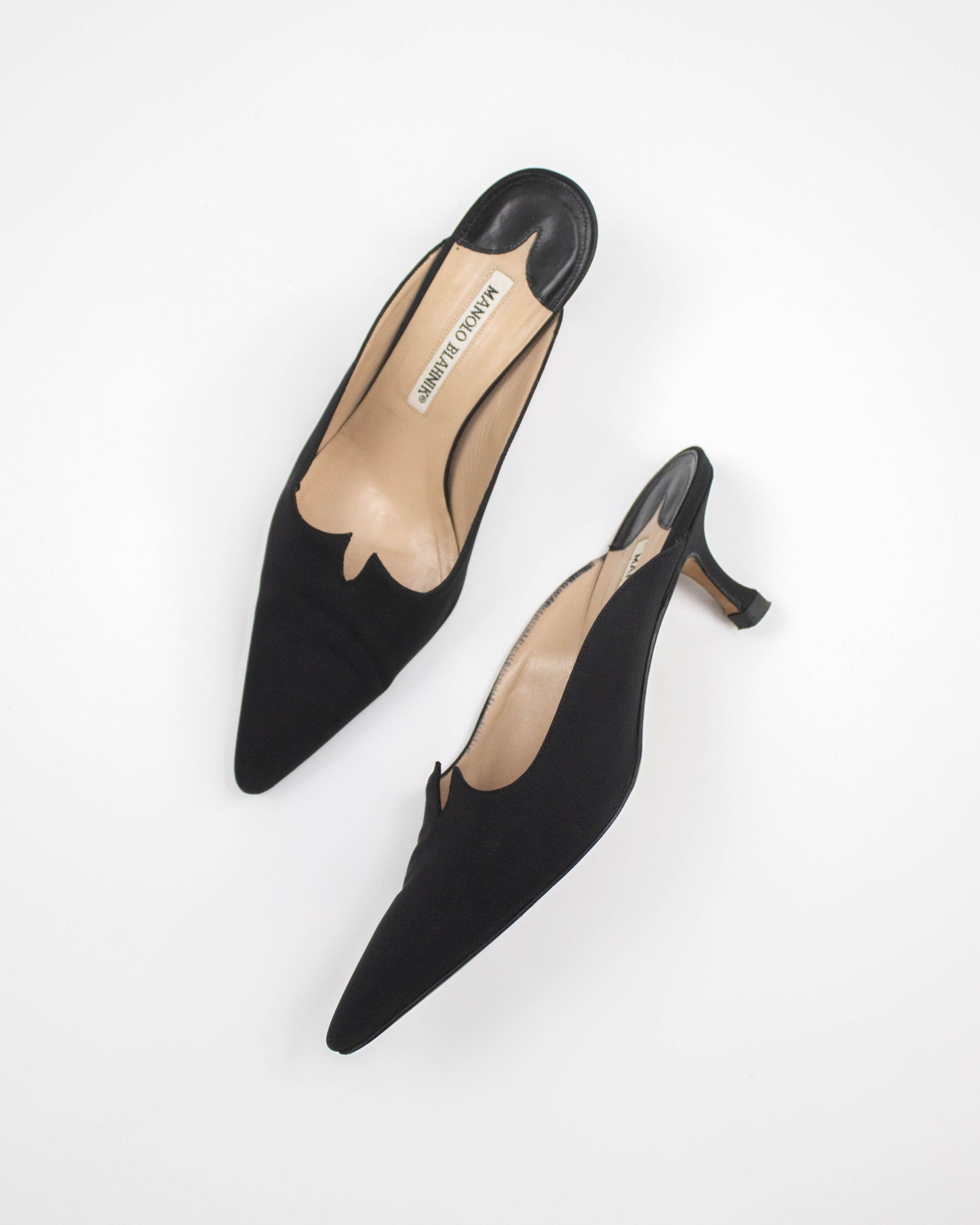 Black low-heeled Manolo Blahnik satin shoes on a white background