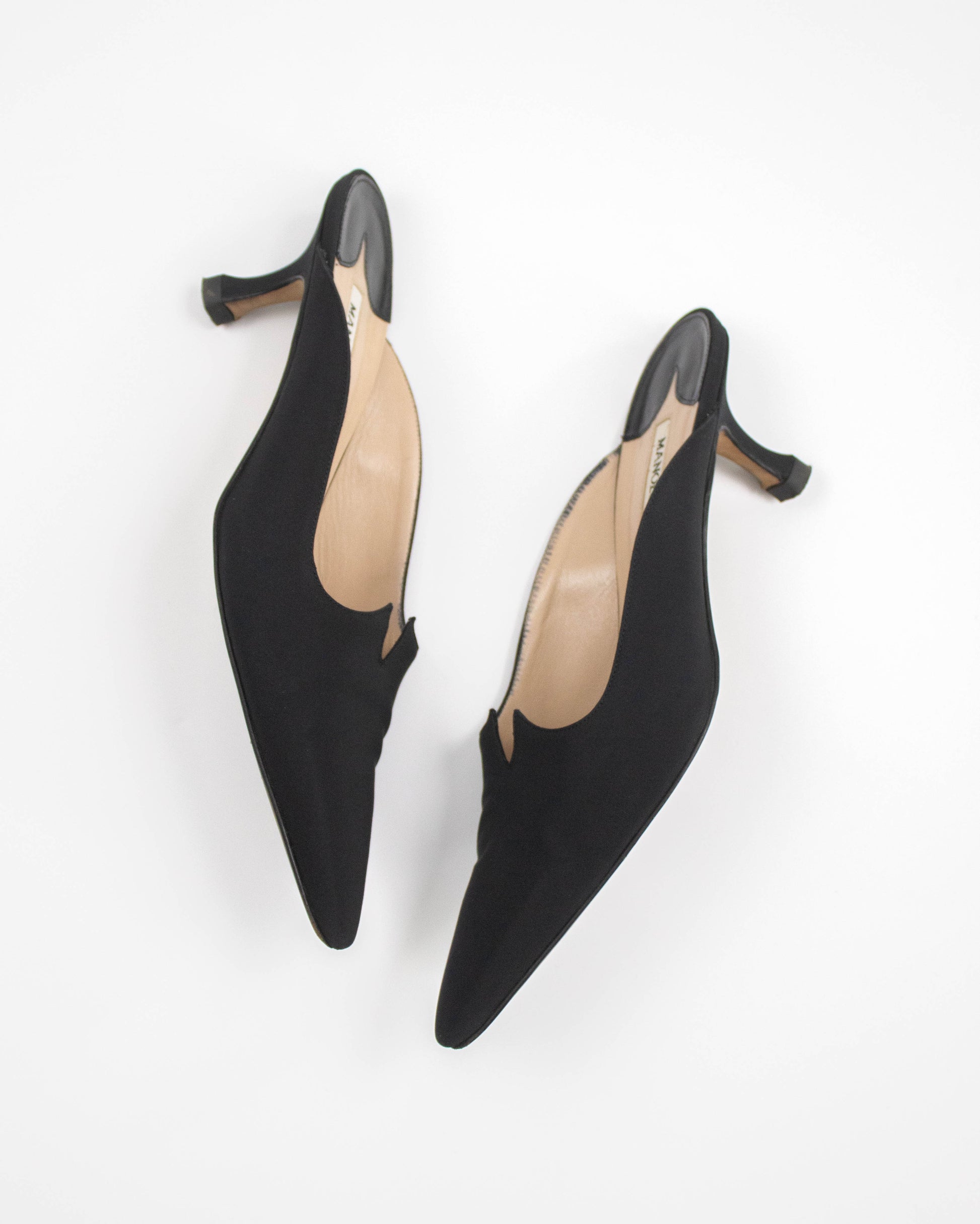 Black low-heeled Manolo Blahnik satin shoes on a white background side view
