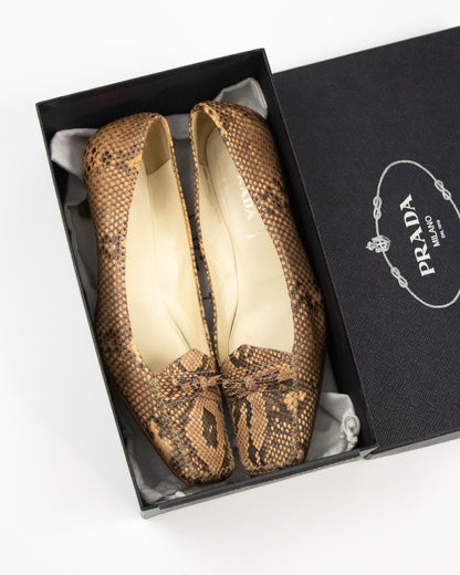 Pair of brown snake print Prada heels on a white background
