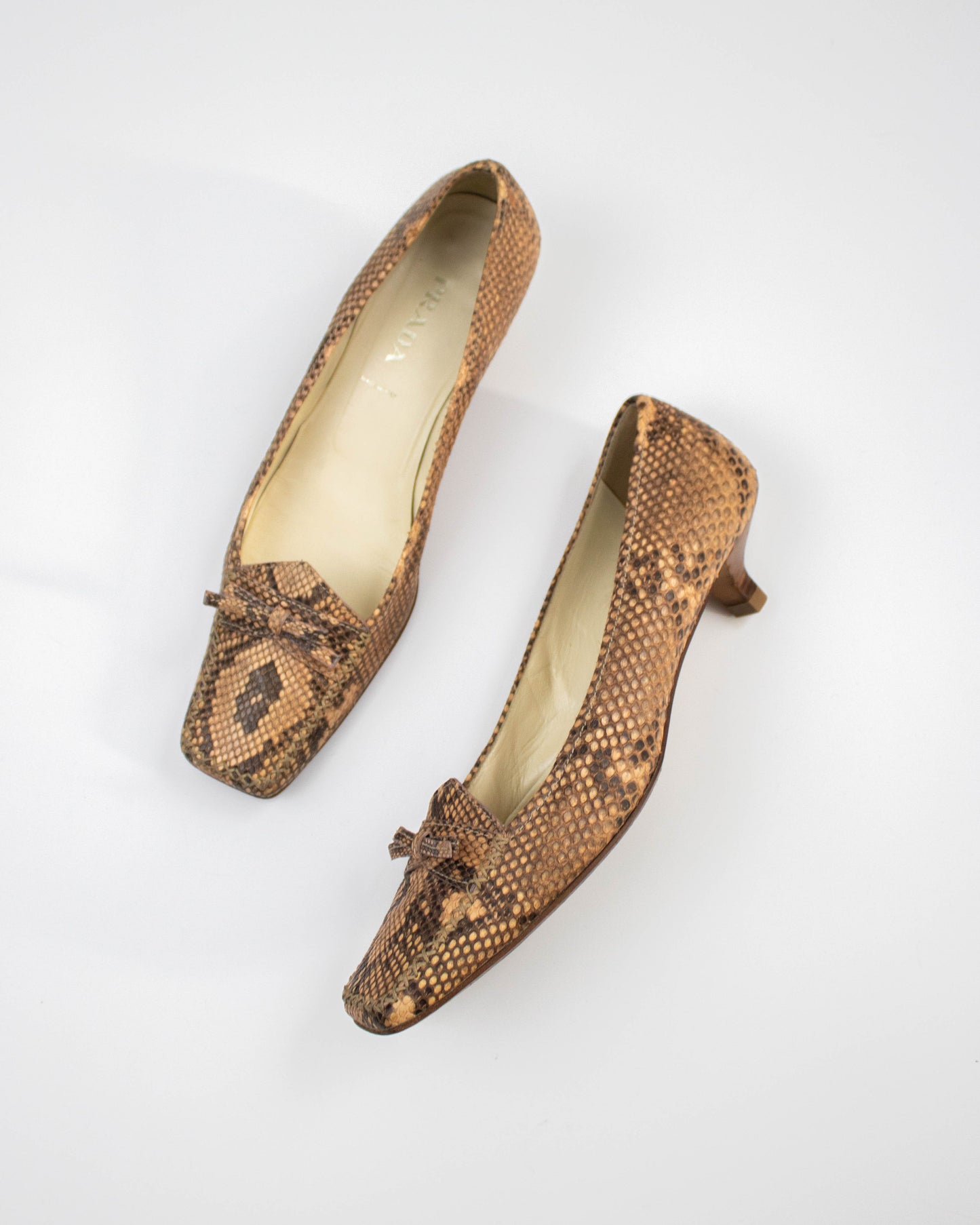 Pair of brown snake print Prada heels on a white background