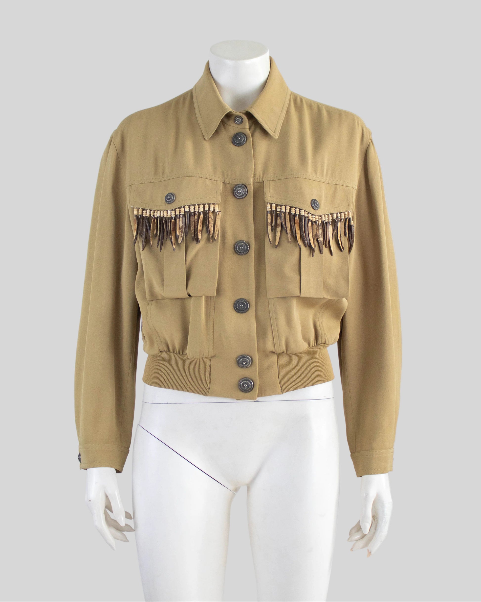Beige Rifat Ozbek jacket with decorative elements on a mannequin against a gray background
