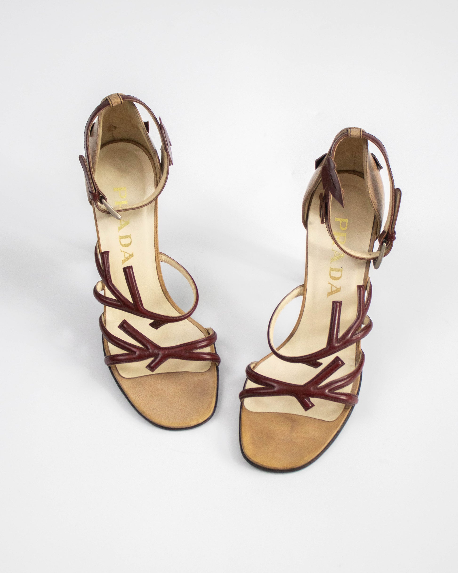 Pair of high-heeled sandals with brown straps on a white background