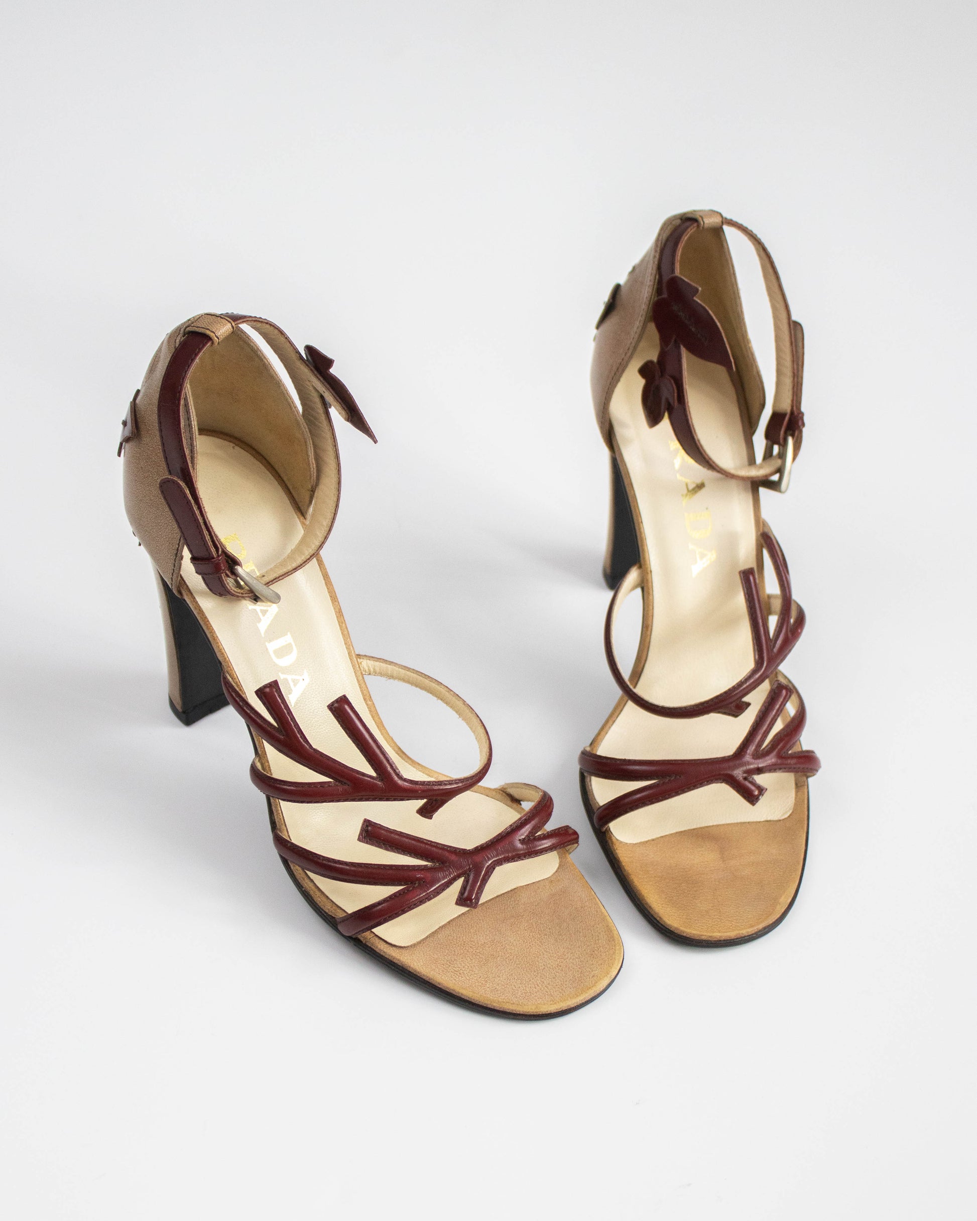 Pair of high-heeled sandals with brown straps on a white background