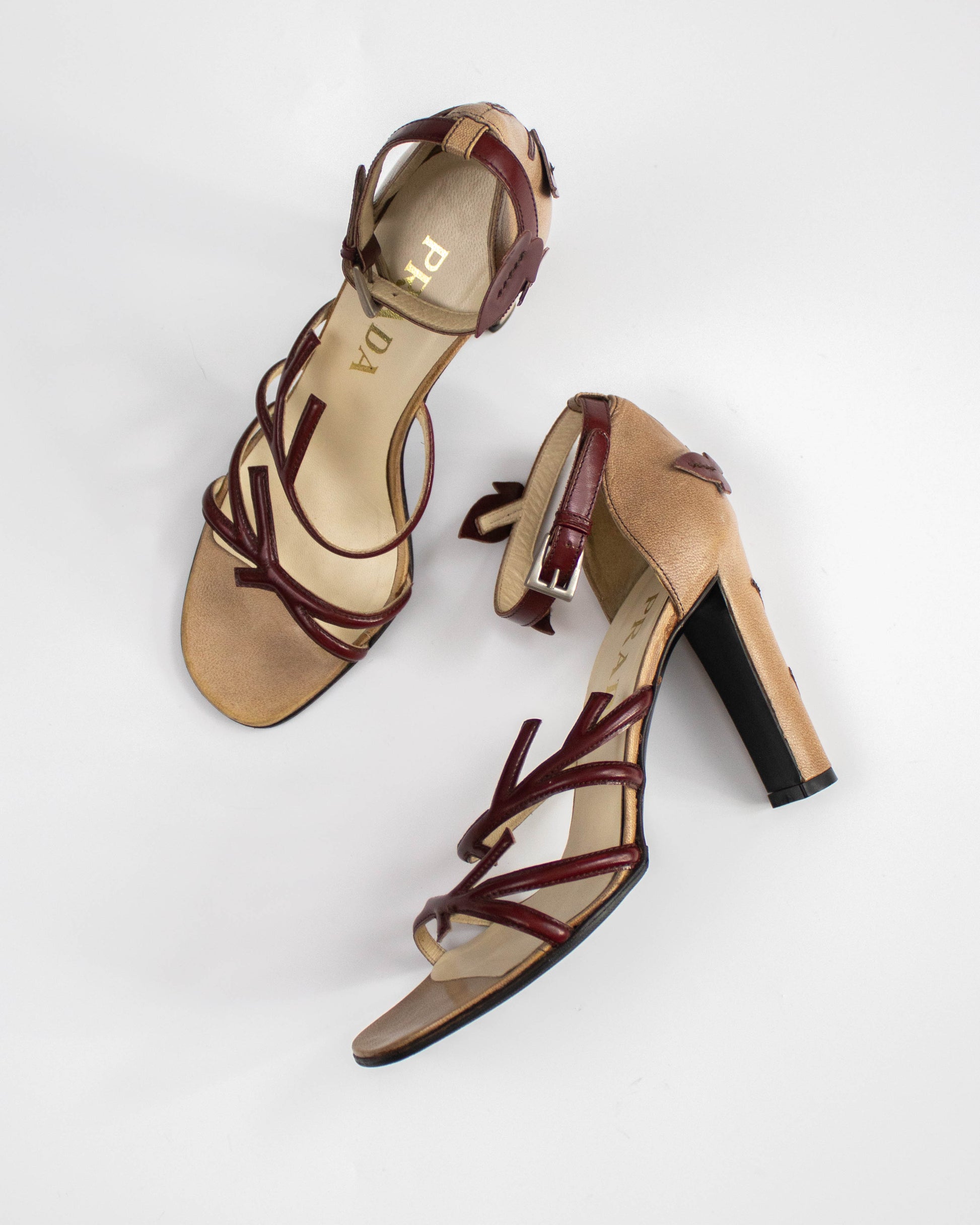 Pair of high-heeled sandals with brown straps on a white background