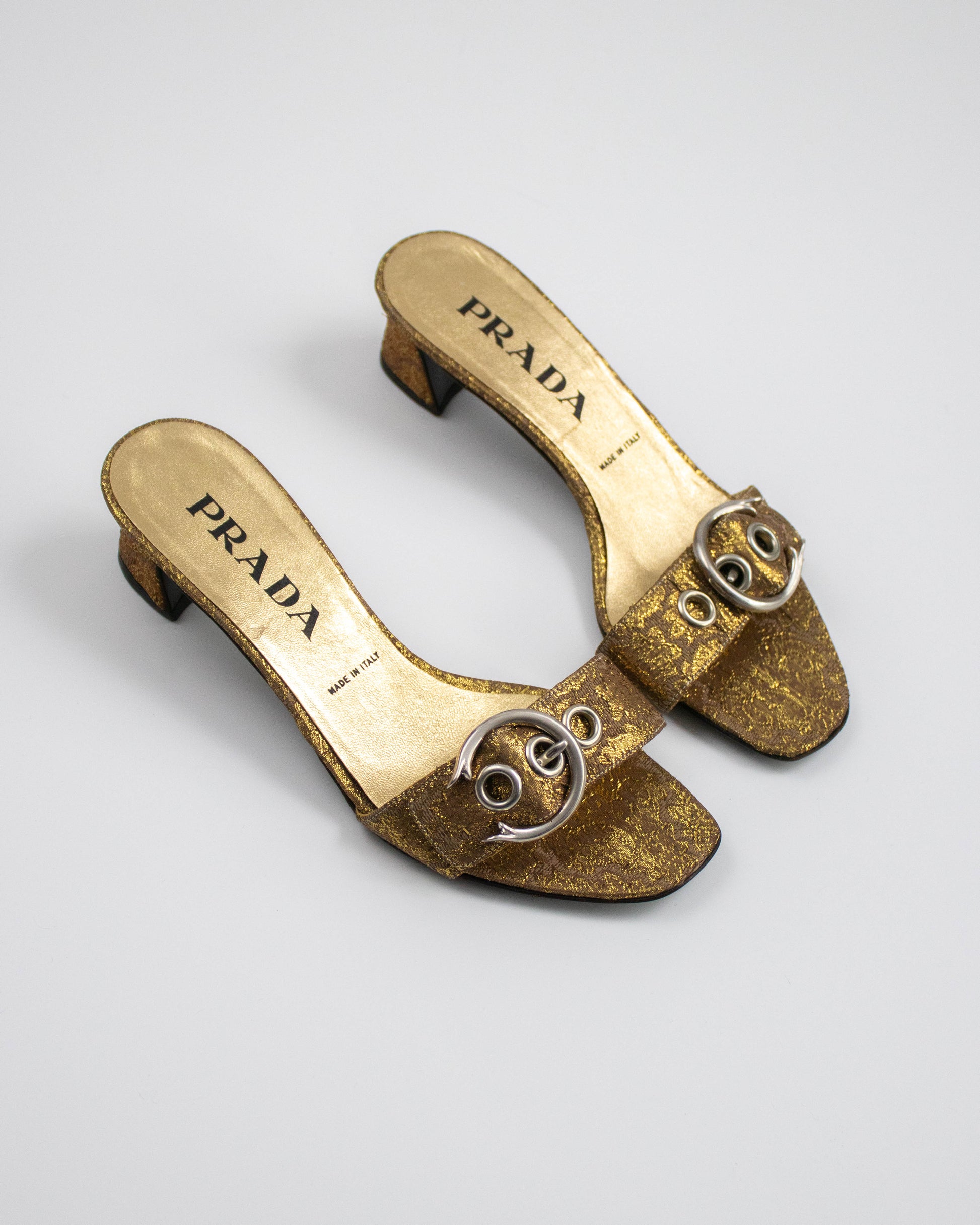 Gold brocade Prada shoes on a white background top view