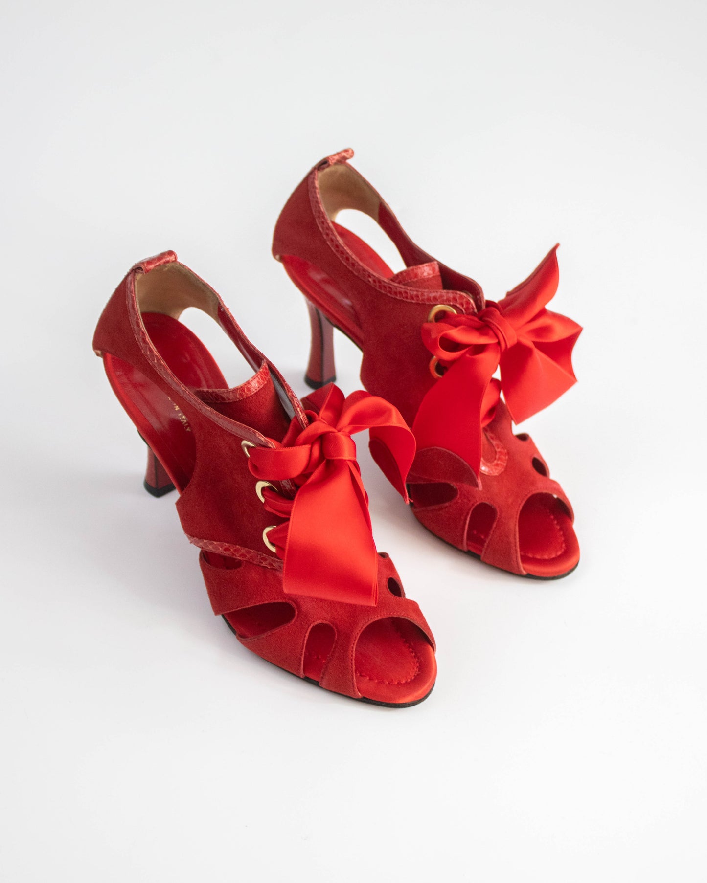 Red high-heeled shoes with ribbons on a white background