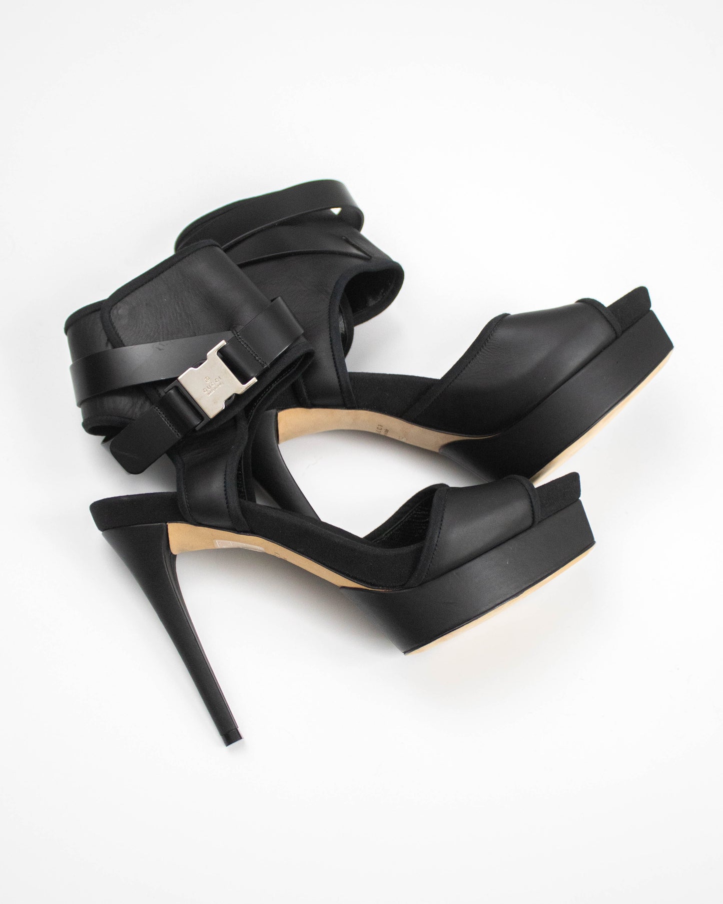 Black high-heeled sandals with a buckle on a white background