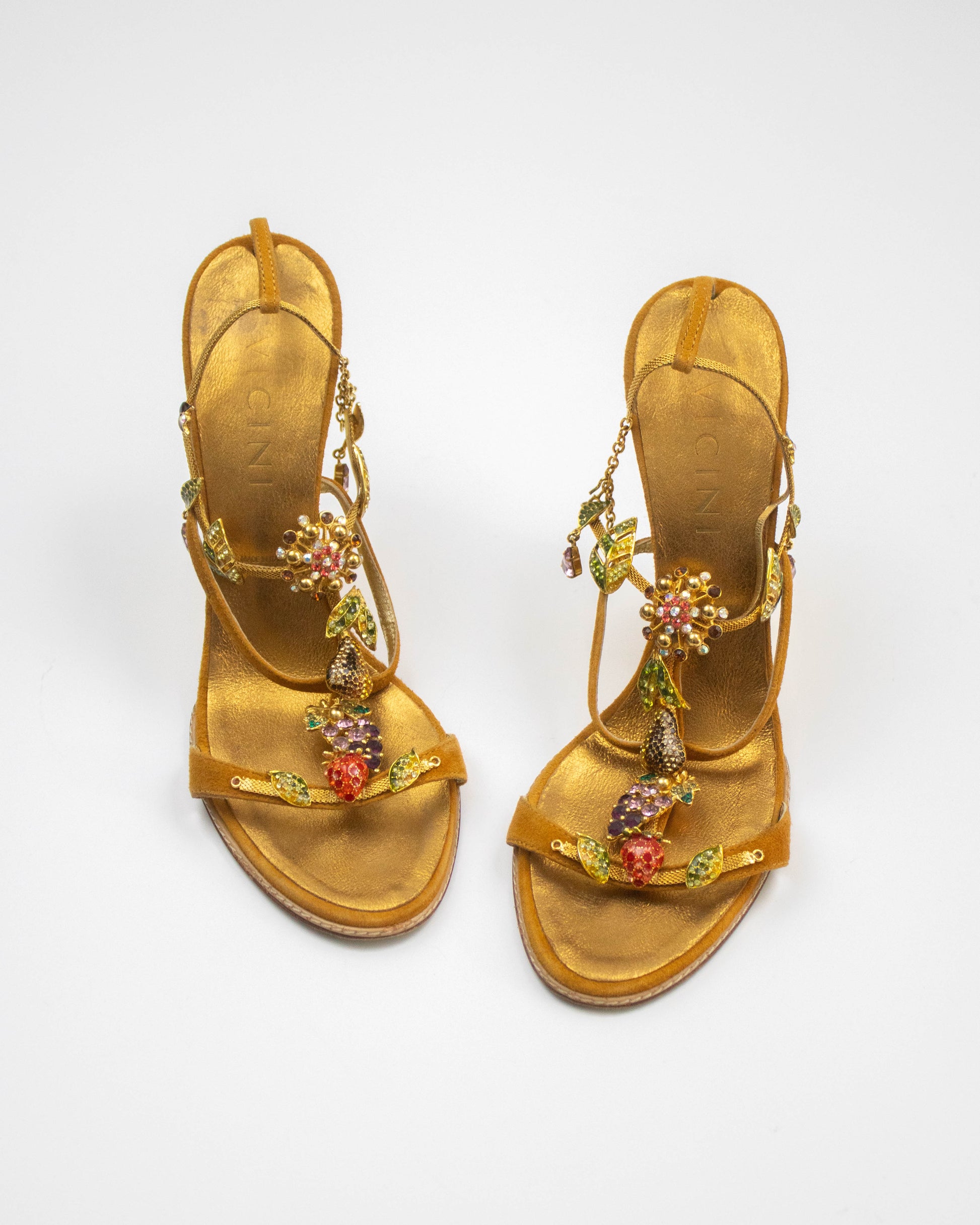 Pair of gold sandals with floral embellishments on a white background